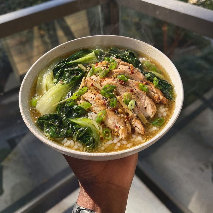 Sliced chicken, rice and greens in a light ginger broth